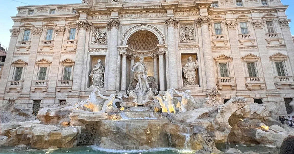 The Trevi Fountain's full facade in soft light, the statues of Oceanus and his attendants above the cascade and the basin