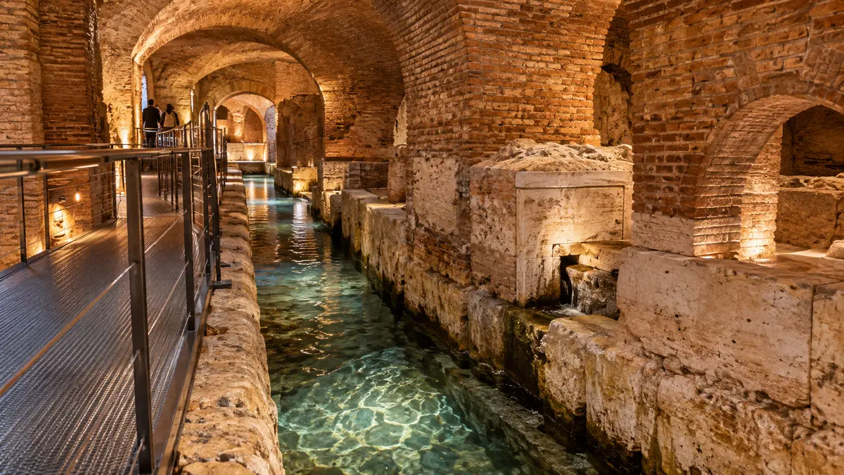 Ein antiker römischer Wasserkanal warm beleuchtet in einem unterirdischen Ziegelgewölbe